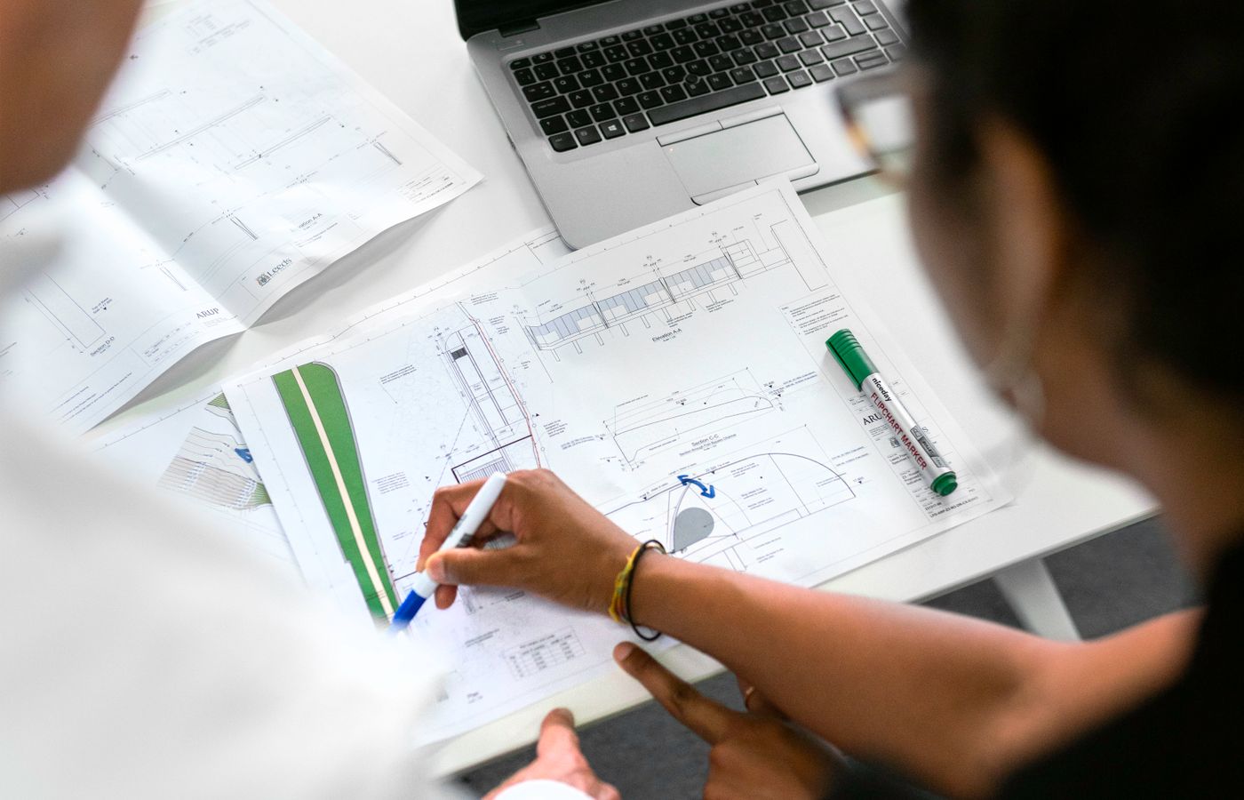 Dos ingenieros revisando planos técnicos y señalando detalles del proyecto